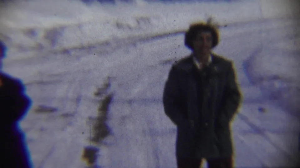 In Chadron, Nebraska in 1959, bundled adults stand apart on a snow-covered street in a soft, blue-tinted 8mm frame.