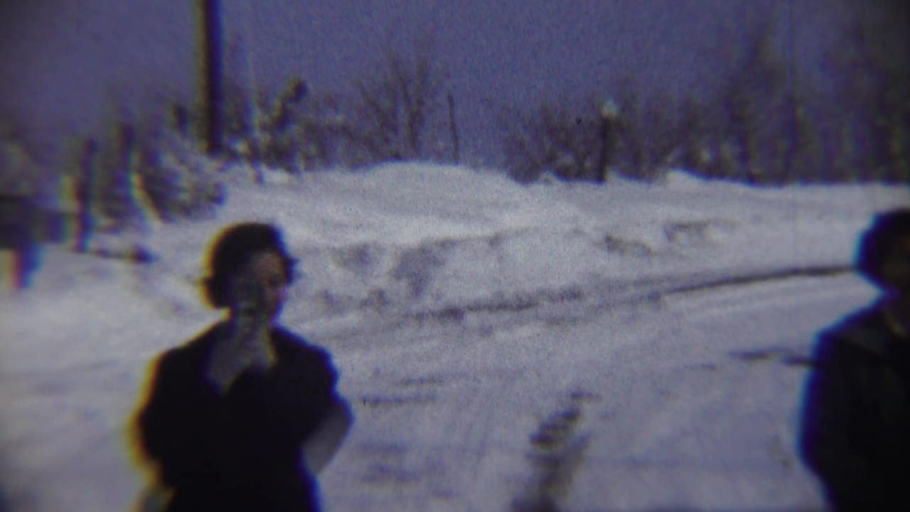 A 1959 Chadron, Nebraska winter frame shows one bundled adult in snow with another person partly cropped at the right edge.