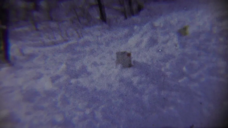 The camera points down across a snowy Chadron, Nebraska winter ground scene, with tracks, snowbanks, and a small dark object visible.
