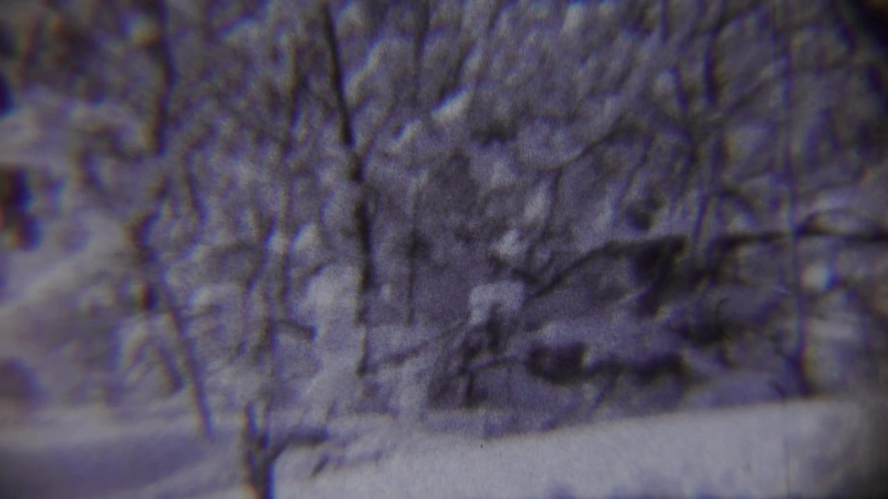 1959 Chadron, Nebraska home-movie frame showing a snowy road, bare trees, and a distant child running through winter snow.