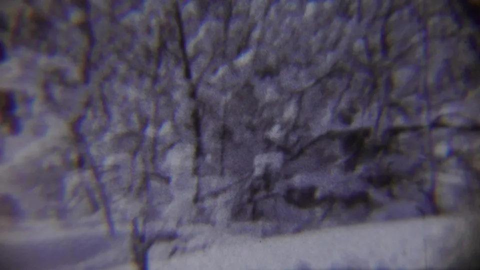 1959 Chadron, Nebraska home-movie frame showing a snowy road, bare trees, and a distant child running through winter snow.