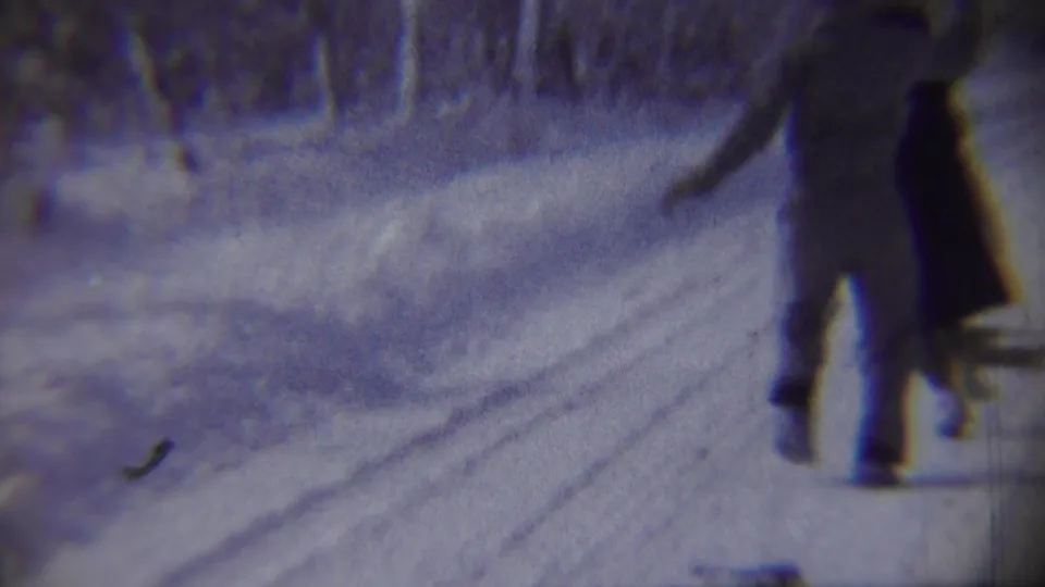 In 1959 Chadron, Nebraska footage, two adults move along a plowed snowy road bordered by winter trees.