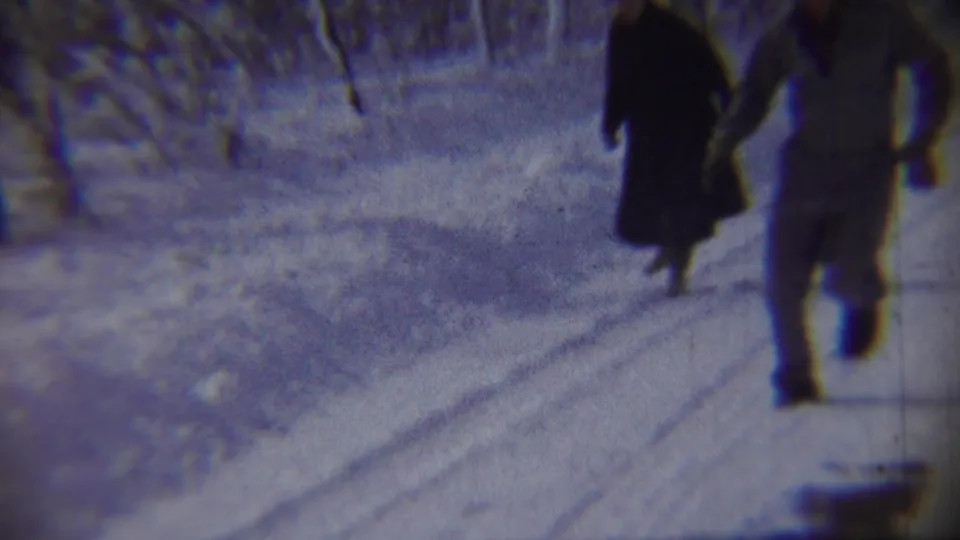 A woman in a dark coat and a man in winter clothing move on a snowy Chadron road, captured with motion blur.