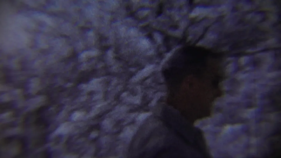 A man in a dark coat appears in profile among snow-laden trees in 1959 Chadron, Nebraska home-movie footage.