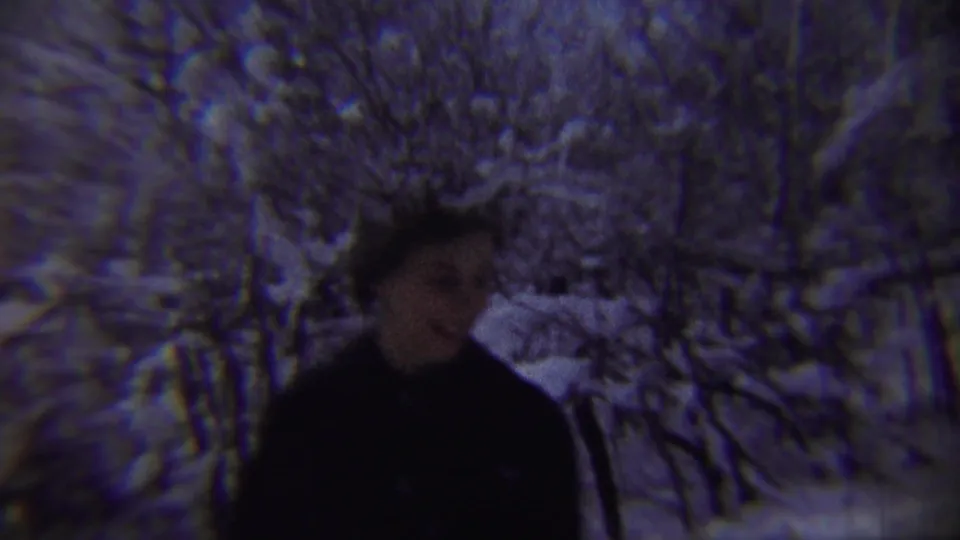 In Chadron, Nebraska, 1959 home-movie footage, a woman in dark winter clothing appears near a snowy street lined with heavily coated trees.