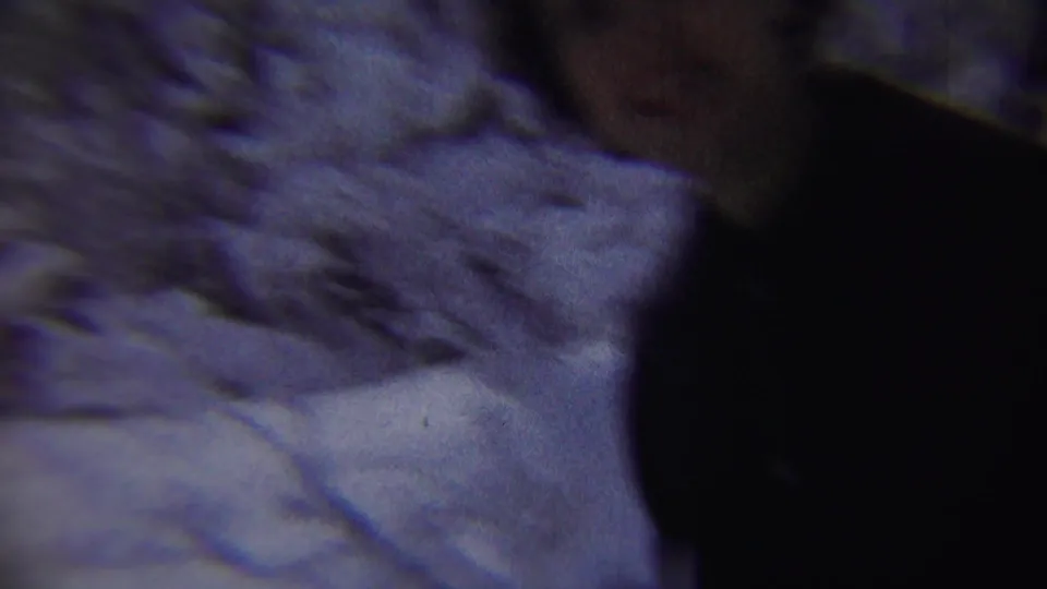 A blurred woman in dark winter clothing passes close to the 8mm camera in the snowy Chadron, Nebraska street scene.