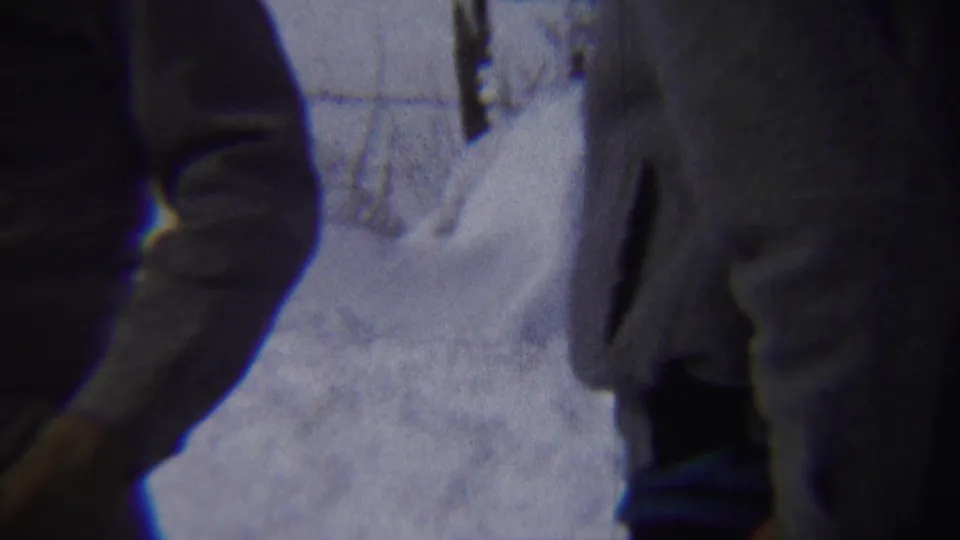 A bundled adult man stands near high snowbanks in a close Chadron, Nebraska home-movie frame from 1959.