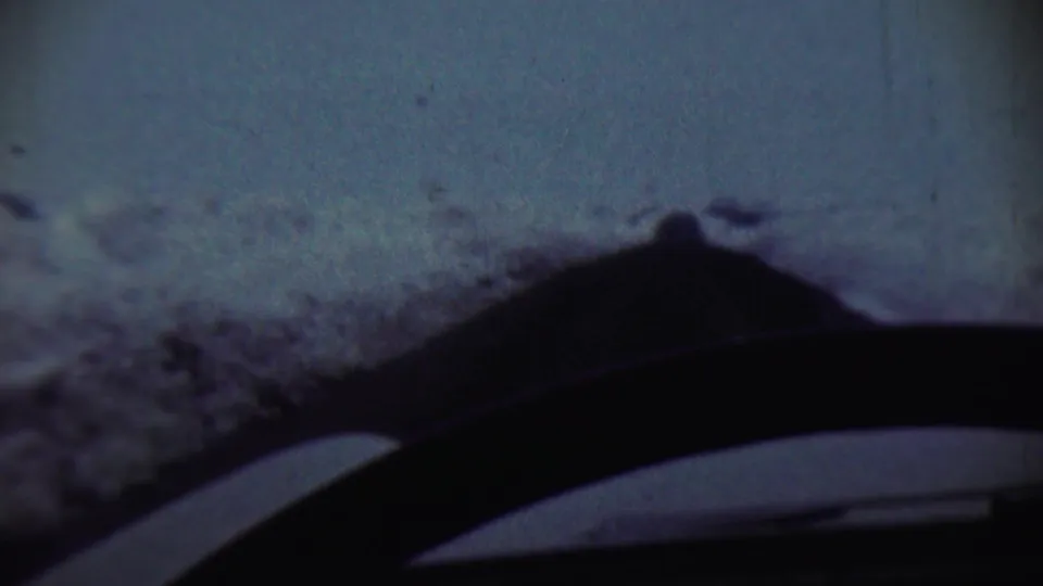 1959 8mm winter travel view from Chadron, Nebraska, looking through a windshield at snowbanks and a dark dashboard or wiper shape.