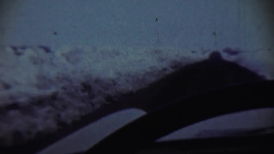 1959 Chadron, Nebraska frame showing a snowy roadside or yard through a vehicle windshield, with dark interior shapes along the lower edge.