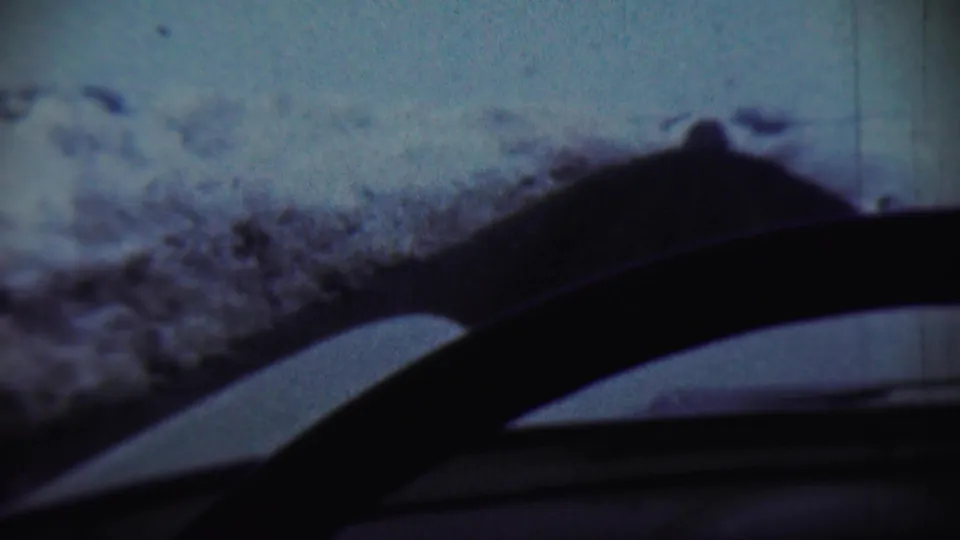 End frame of the 1959 Chadron, Nebraska winter view, with a snow-covered ridge beyond the windshield and wipers cutting across the foreground.
