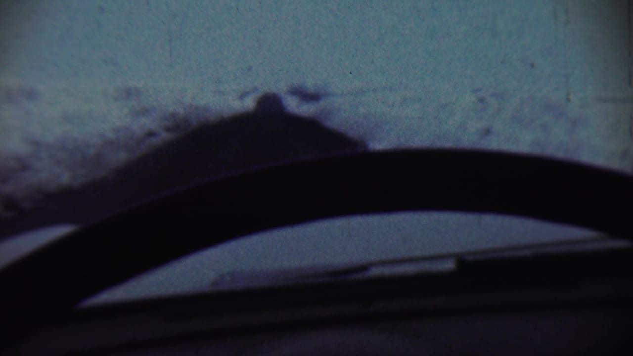 1959 Chadron, Nebraska winter view from inside a car, with a dark wiper and dashboard cutting across the snowy landscape.