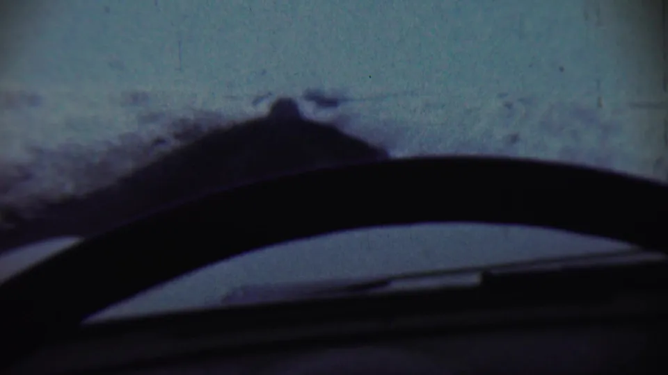 1959 Chadron, Nebraska winter view from inside a car, with a dark wiper and dashboard cutting across the snowy landscape.