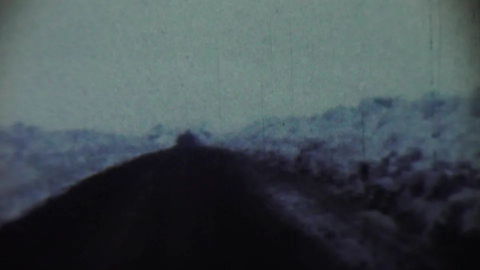 1959 Chadron, Nebraska frame with a soft snowy hillside seen past the dark lower edge of a car windshield.
