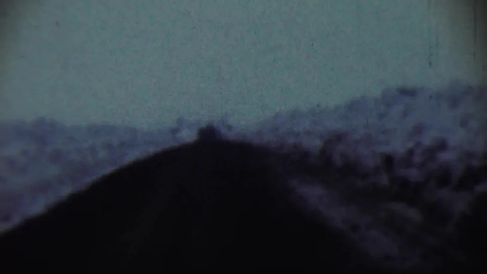 1959 Chadron, Nebraska home-movie still looking through a car windshield at a snow-covered slope in soft focus.