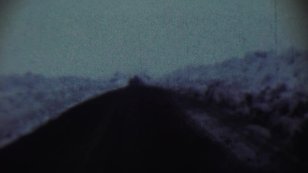 Dark foreground silhouette below a soft hillside and pale blue-gray sky.
