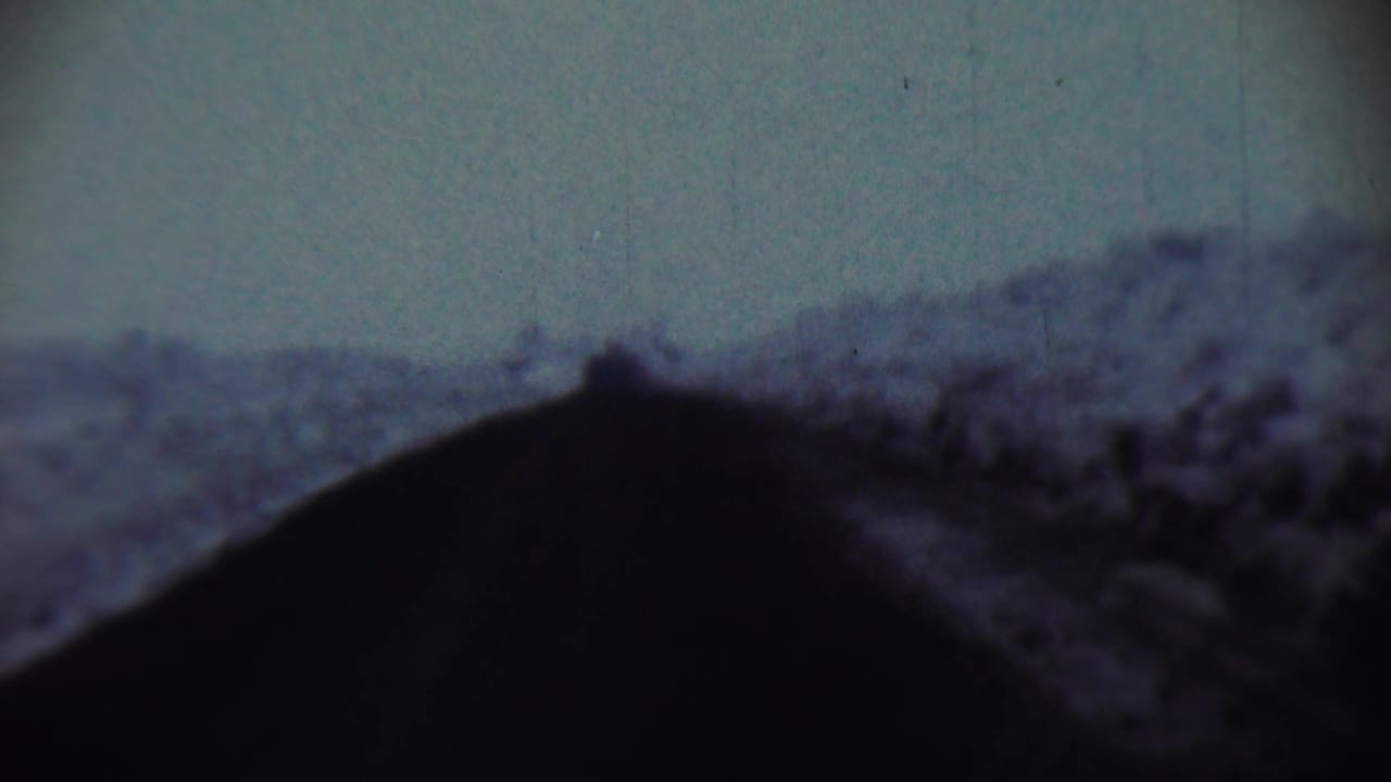 1959 Chadron, Nebraska 8mm frame with a black sloped foreground and indistinct hill shapes beyond it.