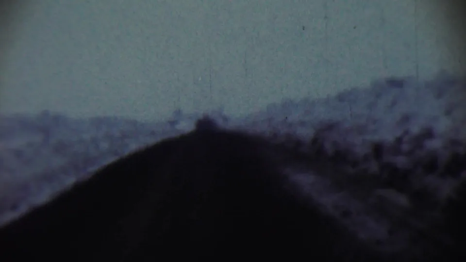 1959 Chadron, Nebraska 8mm frame with a black sloped foreground and indistinct hill shapes beyond it.