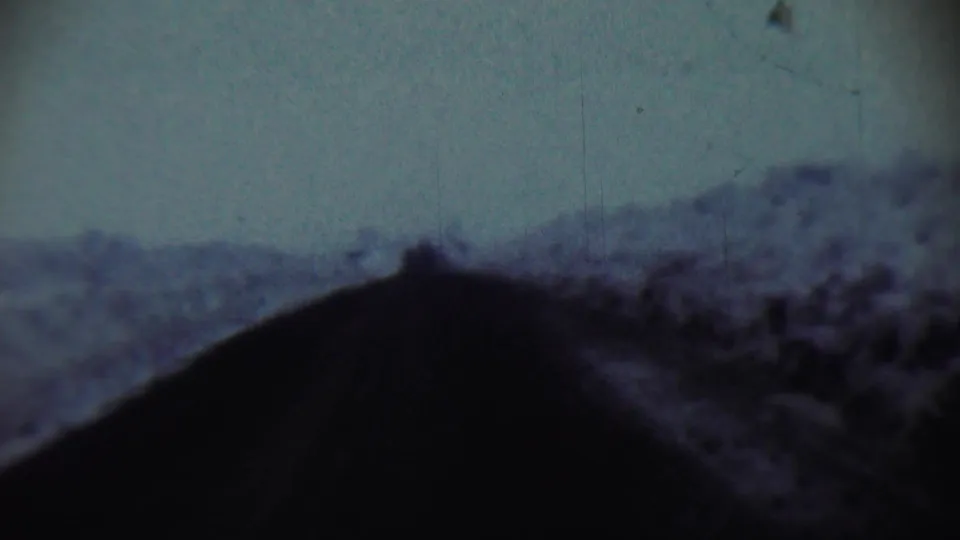 1959 Chadron, Nebraska 8mm frame showing a dark foreground shape and soft, grainy hillside under blue-gray sky.