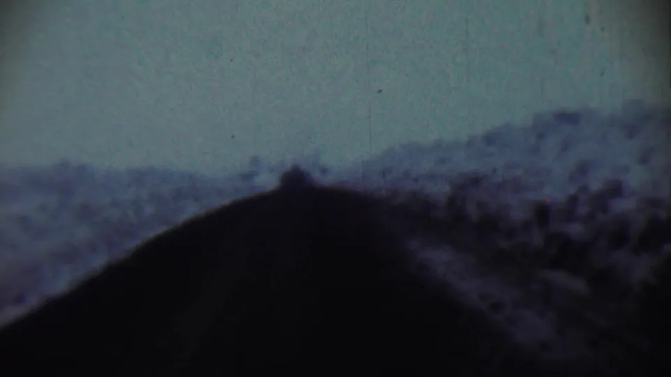 1959 Chadron, Nebraska 8mm frame with a dark ridge-like foreground, indistinct hillside, and visible film grain.