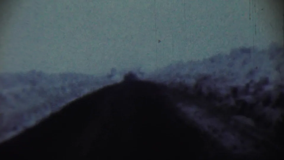 1959 8mm vehicle POV near Chadron, Nebraska, with a dark foreground and hazy rural terrain under a dim sky.