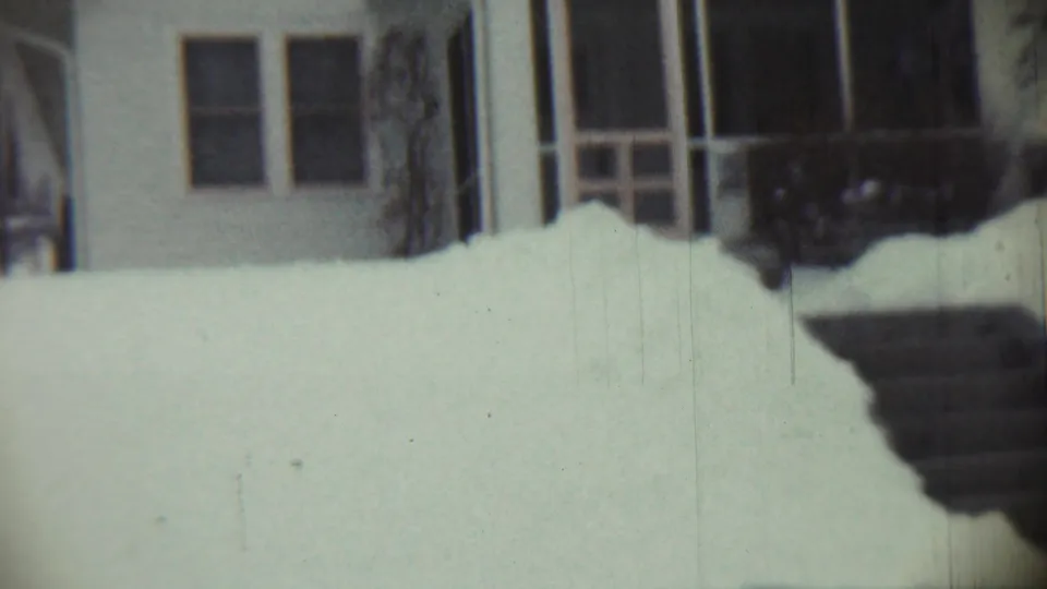 1959 Chadron, Nebraska frame showing deep snow against a house, porch, shrubs, and a darker shoveled or drifted edge.