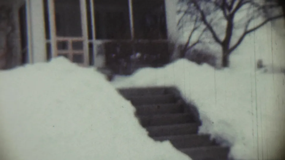 The 8mm frame shows a Chadron house front in winter, with snow piled near the steps and a bare tree at the edge of the yard.
