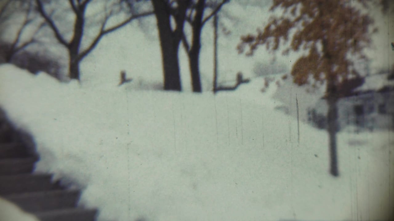 Deep snow surrounds a yard and steps in Chadron, Nebraska, with leafless trees visible through soft 8mm focus.