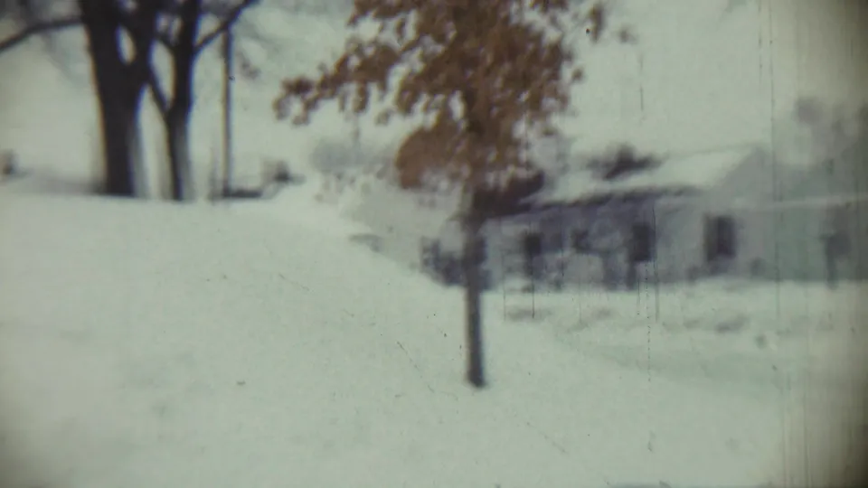 1959 Chadron, Nebraska frame of a snow-covered neighborhood view with a small tree and low houses in the distance.