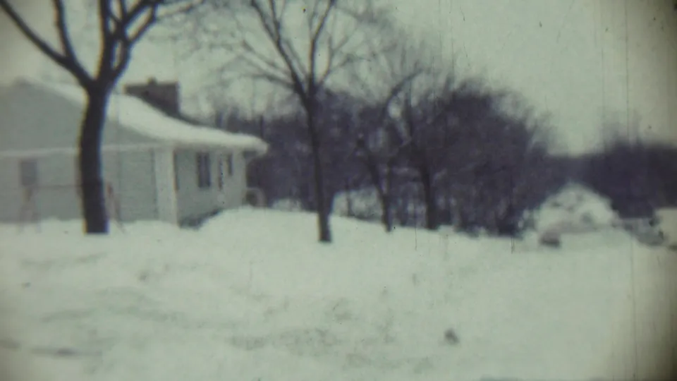 1959 Chadron, Nebraska 8mm frame showing snowy open land, a house edge, leafless trees, and distant woods.