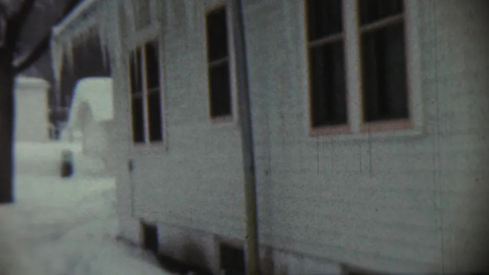 Close 1959 Chadron, Nebraska frame of a house exterior with windows and siding beside deep snowbanks after the blizzard.