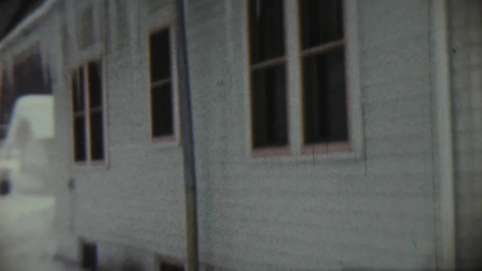 1959 Chadron, Nebraska home-movie still showing white clapboard siding, paired windows, a downspout, and winter snow.