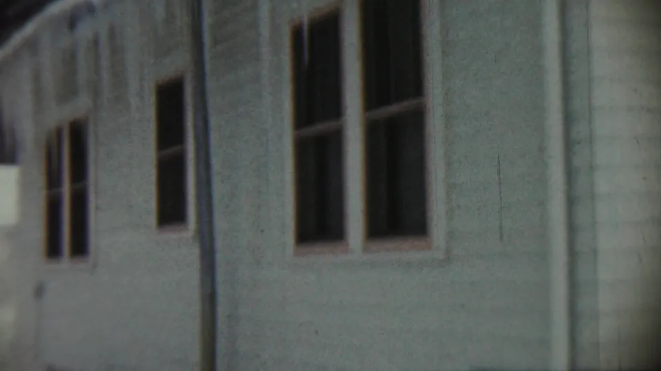 1959 Chadron, Nebraska frame from a soft 8mm pan past a white house exterior, dark windows, and snowy background.