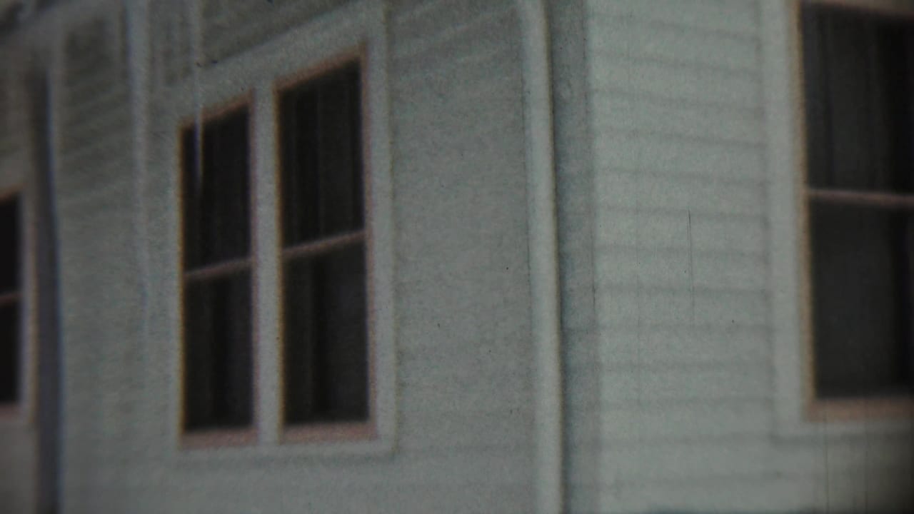 Weathered siding and paired windows on a pale building exterior.