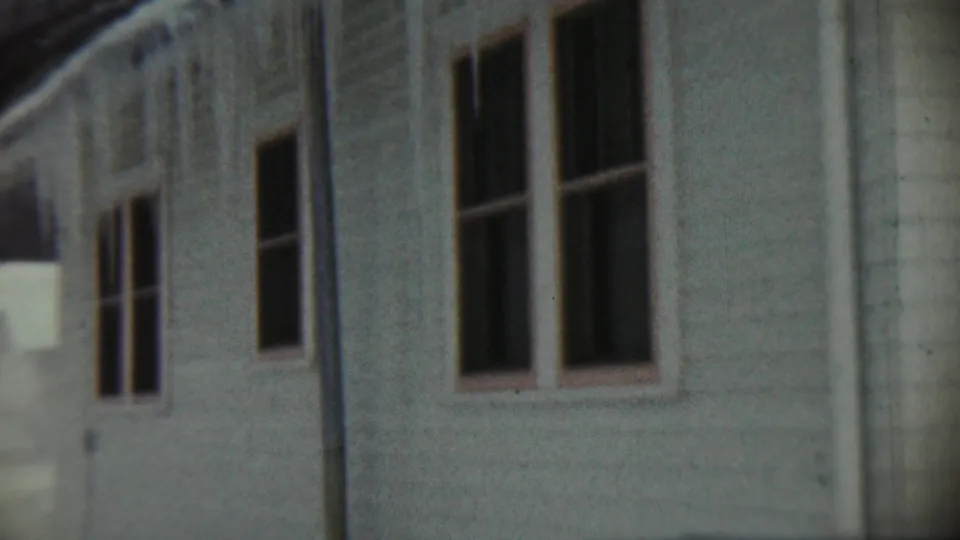 End frame of the Chadron 8mm clip, showing a pale house exterior with multiple windows, trim, and weathered siding.
