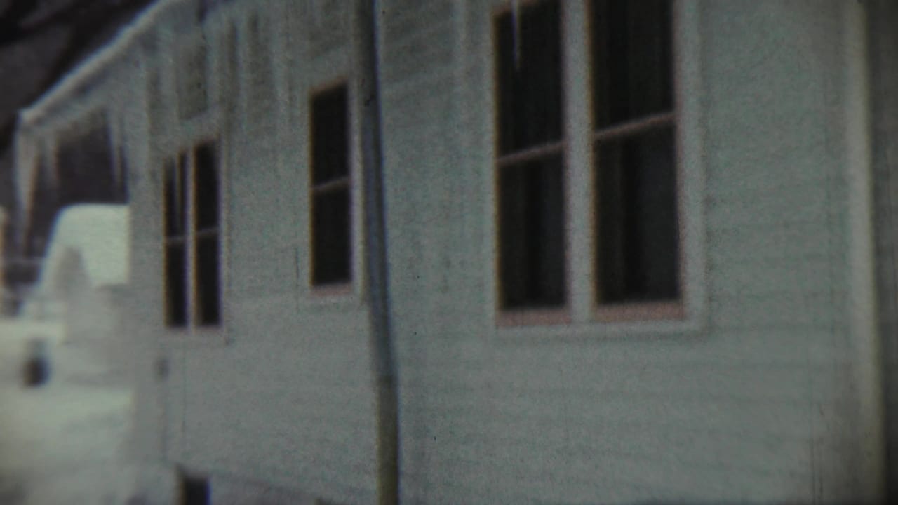 1959 Chadron, Nebraska 8mm frame showing a snow-covered residential exterior with windows and icicles along the roof edge.