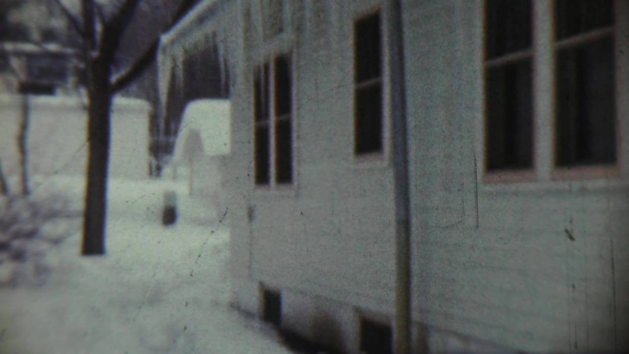 Snowy gap between houses with windows, bare tree, and deep snowbanks.