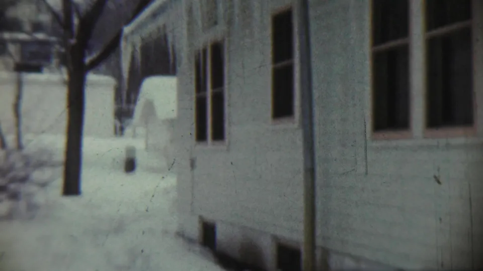 1959 Chadron, Nebraska 8mm frame looking between residential buildings toward a bare tree and snow-covered yard.