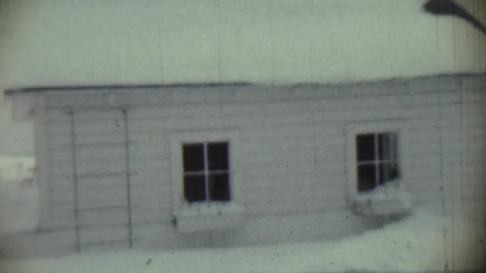 1959 Chadron, Nebraska frame showing a white house exterior in snow, with two dark windows and visible 8mm film texture.