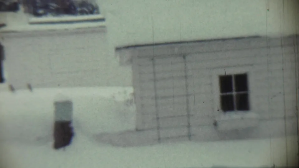 1959 Chadron, Nebraska 8mm frame with a snow-covered residential facade, small dark window, and bright winter ground.