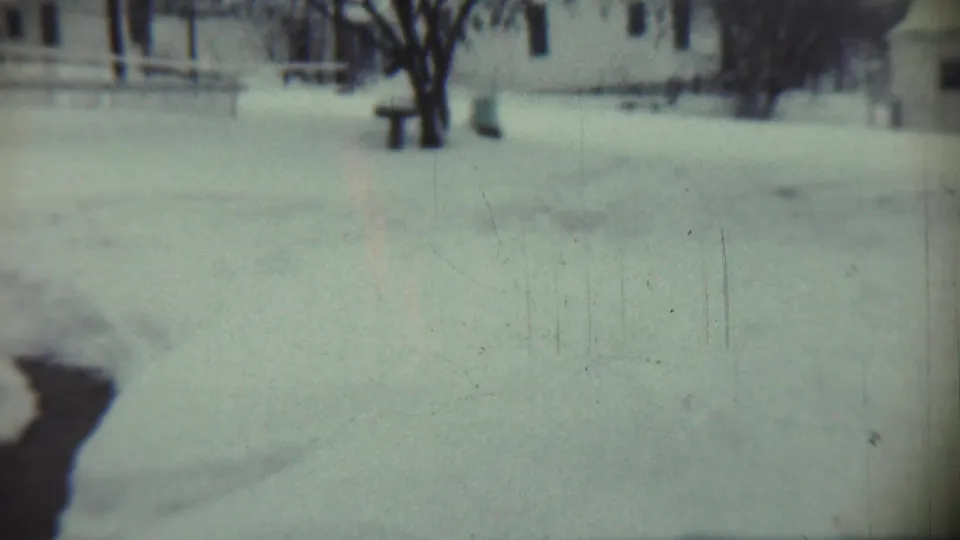 1959 Chadron, Nebraska winter yard scene with deep snow, bare trees, a nearby house, and a dark icy water channel in front.