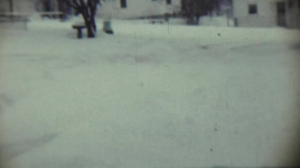 Chadron, Nebraska 1959 home-movie frame with deep snow in a yard, bare trees, and a house softened by film blur.
