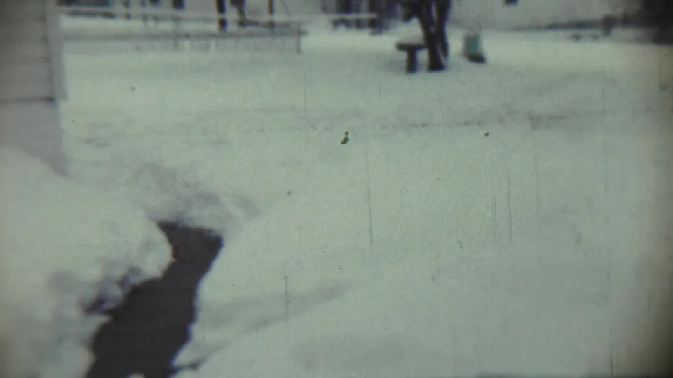 Snowy yard in Chadron, Nebraska, with a dark path or shadow visible across the winter ground in 1959 home-movie footage.