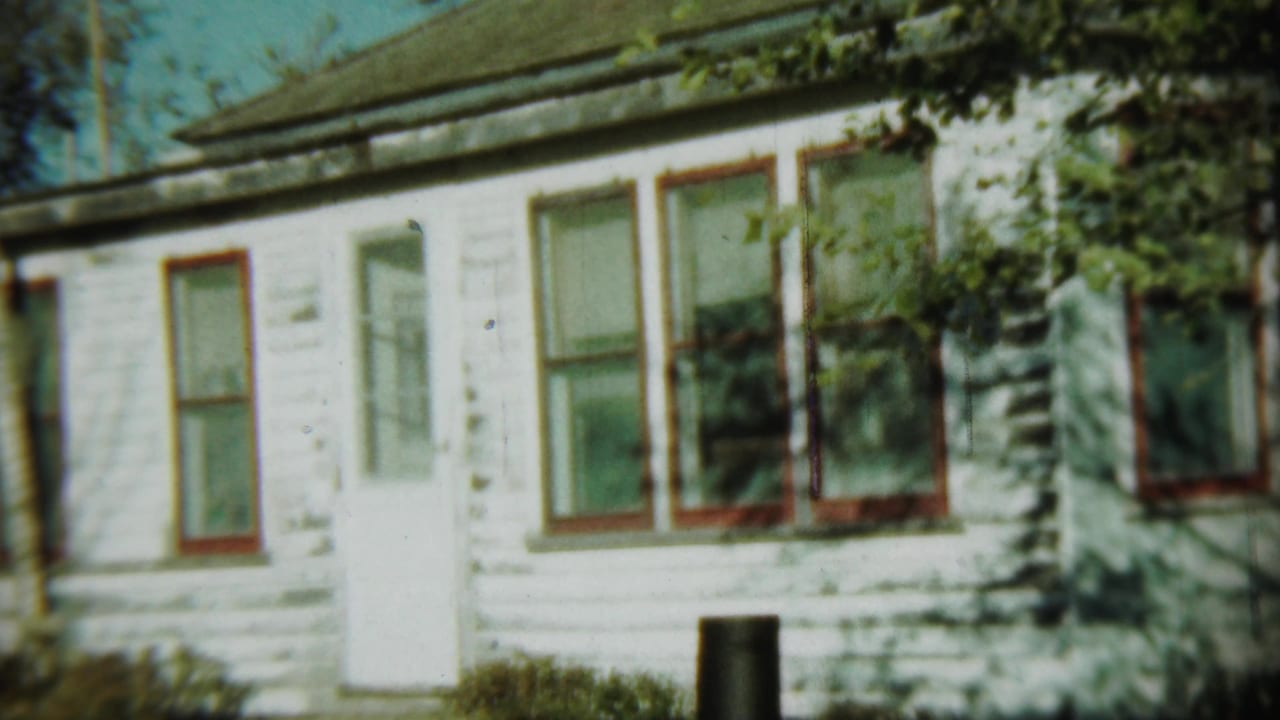 White clapboard building with red-trimmed windows in soft 8mm color.