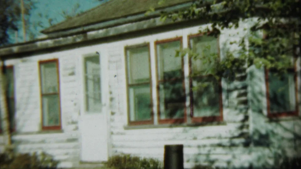 1959 Chadron, Nebraska exterior of a white clapboard building with red-trimmed windows and trees nearby.