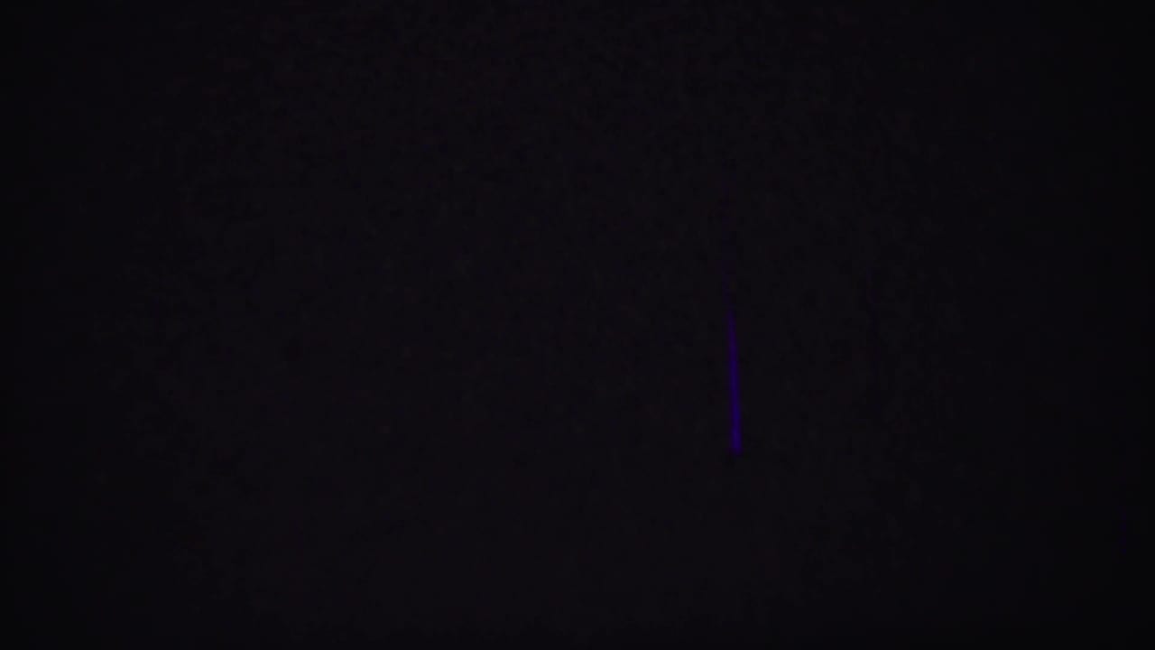Very dark frame with a faint purple vertical line.
