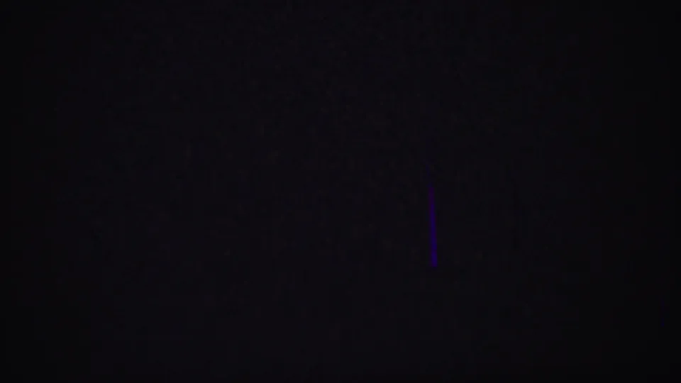 Dark 8mm frame during the clip, showing only a faint purple vertical mark and minimal visible detail.
