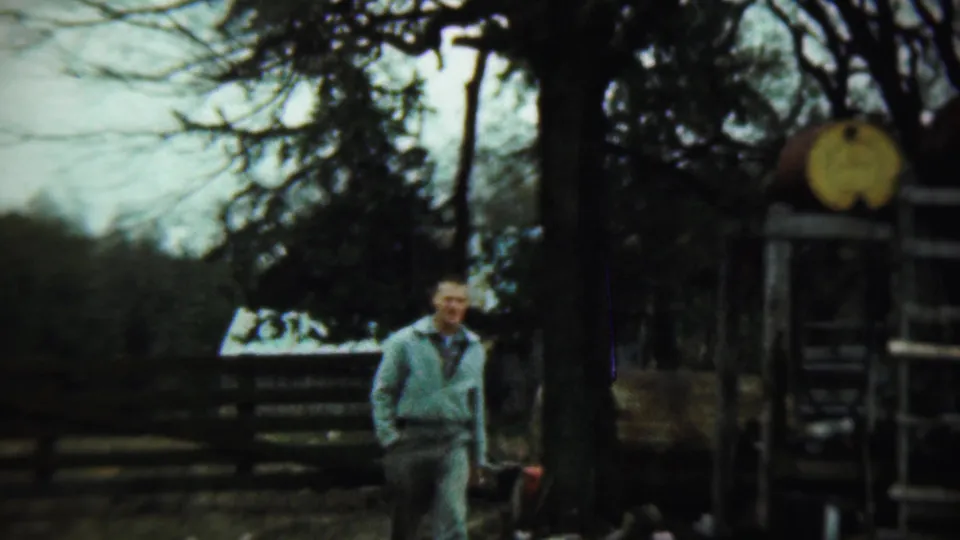 Adult man in light clothing near trees and a wooden structure in Chadron, Nebraska home-movie footage from 1959.