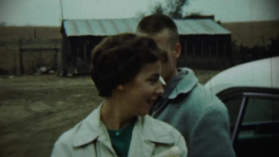 1959 Chadron, Nebraska frame showing a smiling woman near a man, a white car, and rural outbuildings.