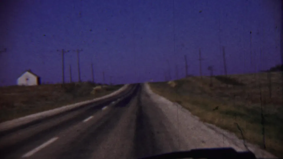 Cheyenne County, Kansas road view from a moving car, with a small white building, utility poles, and open roadside terrain.