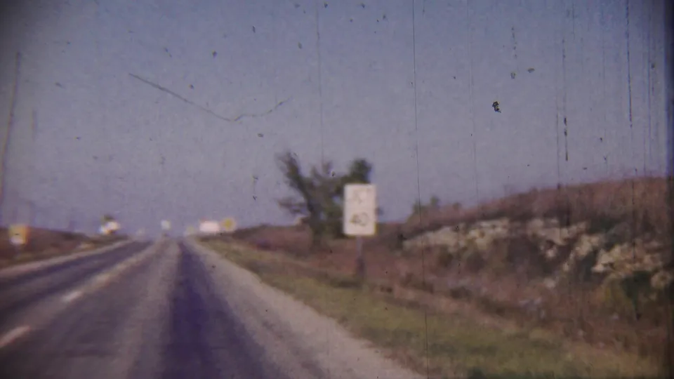 Roadside signs appear beside a rural Cheyenne County, Kansas highway in a 1959 home-movie driving view.